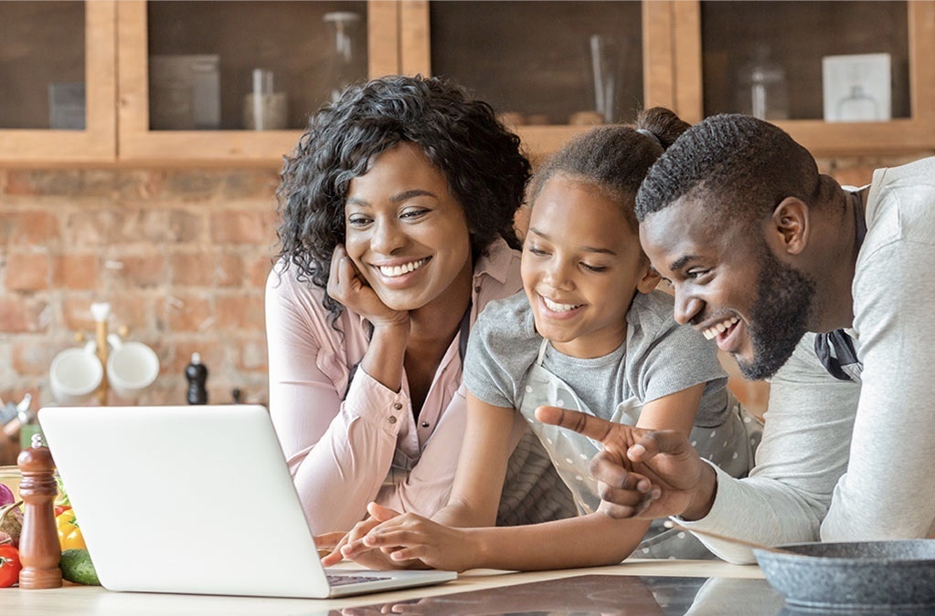 Family smiling and working together on a laptop