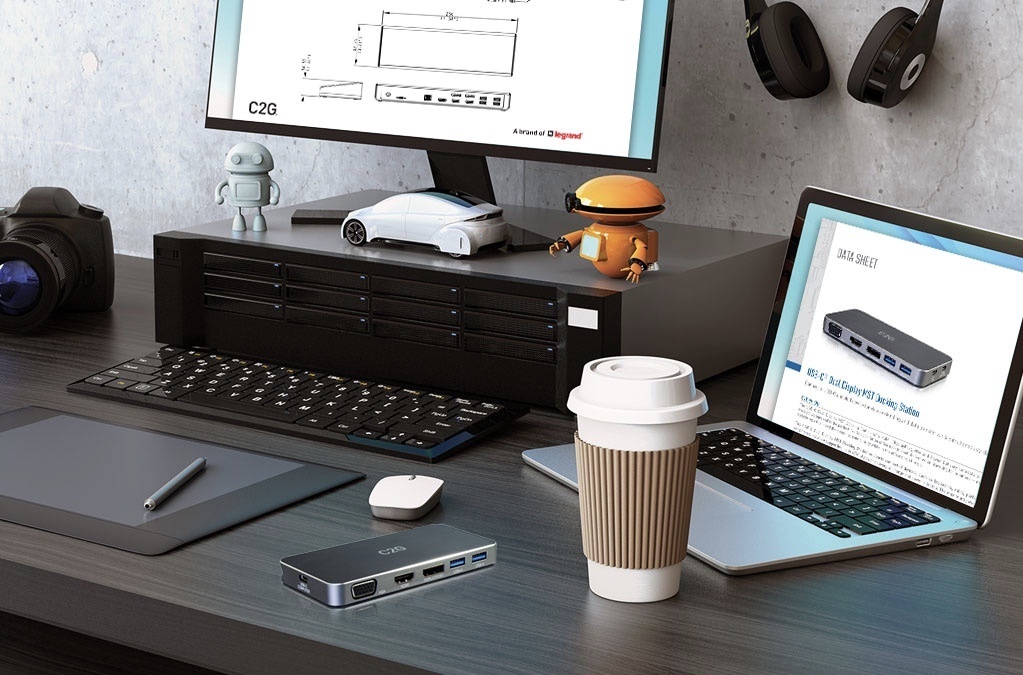Office desk with a laptop, desktop, keyboard and coffee